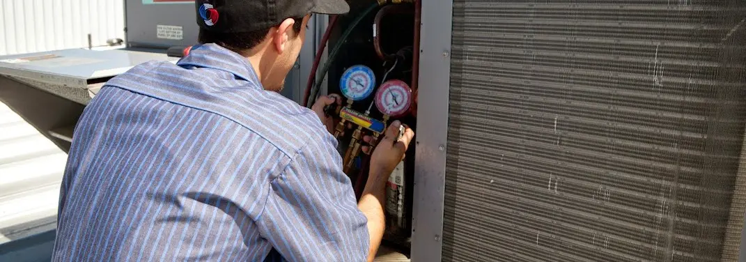 HVAC technician servicing a condenser unit in Grandville