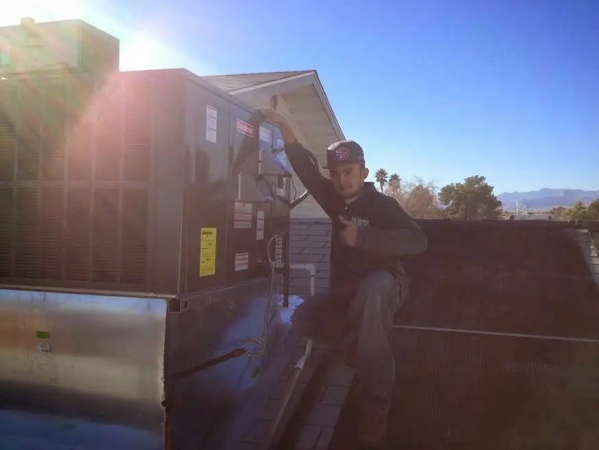 HVAC technician performing Heat Pump Repair on a rooftop unit in Grandville